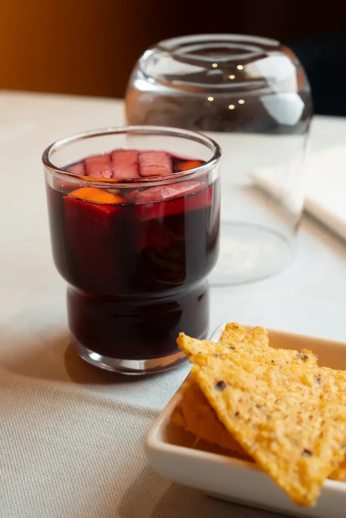 Un bicchiere di sangria di fianco ad alcuni nachos su un tavolo con una tovaglia bianca