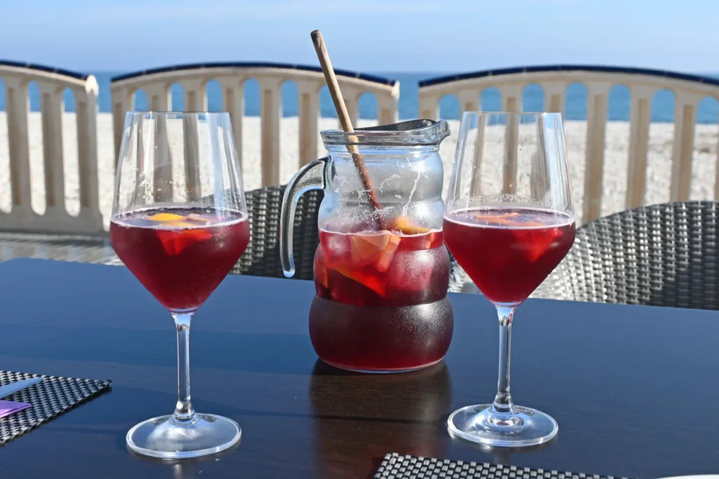 Una caraffa di sangria con due bicchieri della stessa su un tavolo con vista mare